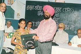 The Project Officer of the Education Department, Mr Bahadur Singh, hands over a bag and stationery to a student of the slum school at Kajheri in Chandigarh