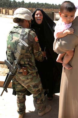 An Iraqi woman laughs as she is frisked by an American woman soldier in Bakuba