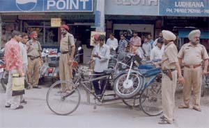 Policemen take away a two-wheeler from the parking lot in front of Calibre Plaza