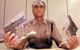 A Delhi Police officer showing the arms seized from the Chhota Nawab gangsters