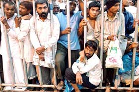 Hindu devotees blocked by a barricade wait for their turn to take holy dip 