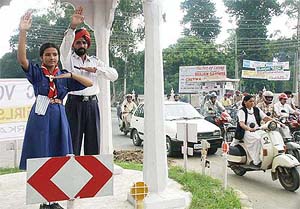 A girl scout learns traffic rules and signals from a traffic police at a busy crossing in Amritsar