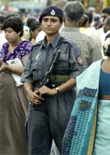 A woman police commando holds a machine gun as she keeps watch on devotees 