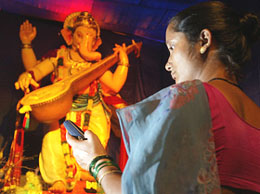 A woman sends an SMS on her mobile phone before a Ganesh idol