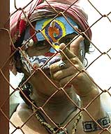 An anti-globalisation protester mocks police officers through a fence at a roadblock in Cancun
