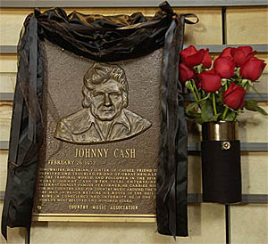 The hall of fame brass plaque honoring country music singer Johnny Cash is draped in black with red roses 