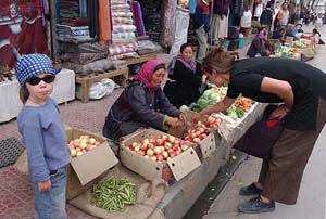 An English woman buys apples on the street of Leh while a young girl accompanying her looks on