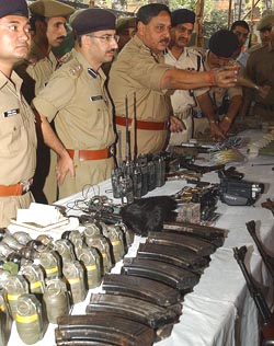 Police officers display arms and ammunition recovered from hideouts of militants in Srinagar on Wednesday.