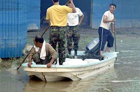 South Koreans use a boat at a village flooded by Typhoon Maemi in Changnyong