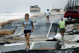 Beachfront resident Kathy Dewey walks over a buckled highway