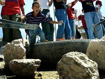 A Palestinian boy shouts from behind a barricade