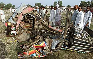 Residents gather near the wreckage of the ill-fated bus near Malakwal town