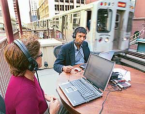 Anoop Gupta (R), corporate vice-president at Microsoft, sits at an elevated train station platform in Chicago's Loop district with Corinne Martinez of Microsoft to demonstrate a new service called Microsoft Office Live Meeting. 