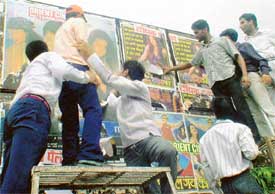 ABVP members of Arya College tear film posters from a hoarding outside the college