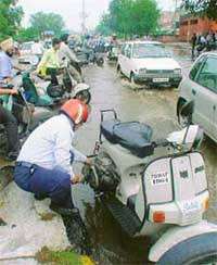 A scooterist tries to remove a snag in the scooter near Vishwkarma Chowk