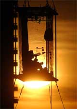 US illusionist David Blaine takes a drink of water while suspended in a glass box hung from a crane by Thames river in London 