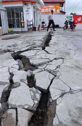 A man walks over cracks in the compound of a gas station