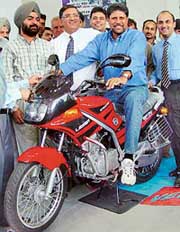Cricketer Kapil Dev poses on a new model of Kinetic motor cycle launched in Chandigarh on Friday.
