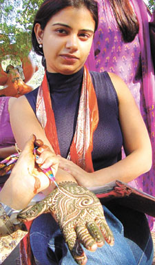 A girl gets a mehndi imprint on her hand outside Hanuman Temple on Baba Kharag Singh Marg on the eve of Karva Chauth