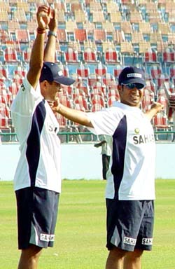 Sachin Tendulkar and Virender Sehwag perform stretching exercises during a practice session at PCA Stadium