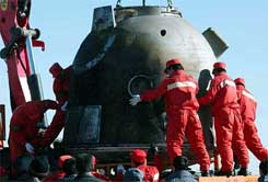 Workers in northern China's Inner Mongolia load the capsule of Shenzhou 5