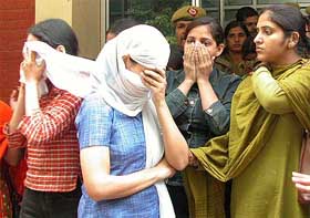 Three of the six women, who were arrested in connection with flesh trade from a hotel in Delhi, try to cover their faces at the Chanakyapuri police station in New Delhi on Friday.