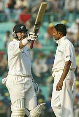 New Zealand batsman Craig McMillan raises his bat on scoring a half century as Anil Kumble looks on during the second day of their second Test match in Mohali.  Reuters photo