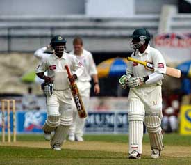 Bangladeshi batsman Hannan Sarkar and Javed Omar leave the ground after a downpour in Dhaka 