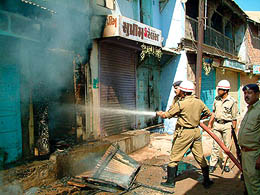 Firefighters hose down the flames after a fresh communal violence