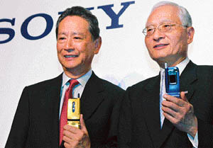 Sony Corp Chief Executive Nobuyuki Idei (L) and NTT DoCoMo Inc Chief Executive Keiji Tachikawa smile as they hold up image mock-up handsets at a news conference in Tokyo after they announced setting up a joint venture to develop smart-card chips allowing consumers to use their cellphones as an electronic wallet and commuter pass
