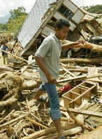 A resident examines houses damaged from a flash flood