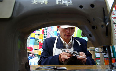 A tailor works at an outdoor market in Beijing
