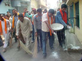 Shiv Sainiks sweep a road in Ludhiana in protest against the alleged inaction of the Municipal Corporation