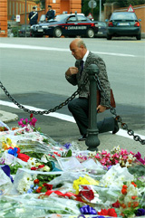A man prays on his knees after laying flowers outside the Carabinieri headquarters in Rome