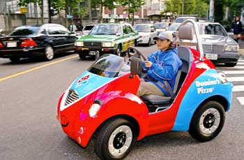 A Domino Pizza shop employee drives an electric vehicle named Qi, produced by Japanese toy-maker Takara, to deliver pizzas in Tokyo on Friday.