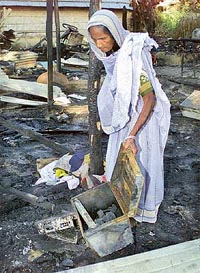 A woman collects belongings from the debris of her burnt house in Guwahati on Wednesday