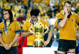 Dejected Australian players George Smith, Jeremy Paul and Justin Harrison stand on the podium during the presentation ceremony after the Rugby World Cup final match against England at the Olympic stadium in Sydney