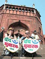 Two foreign tourists hold heart-shaped placards, reading "Id Mubarak", at Jama Masjid in Old Delhi
