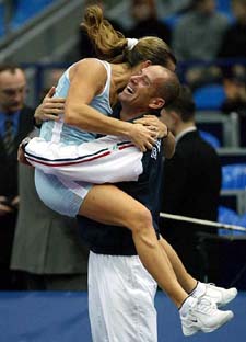 Amelie Mauresmo of France jumps onto non-playing captain Guy Forget after winning the Federation Cup final against USA in Moscow 