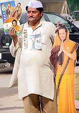 A Congress supporter walk with Sonia Gandhi's posters and the party symbol during campaign in Delhi on Tuesday. 