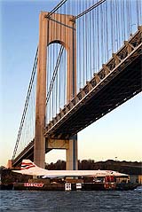 A British Airways Concorde is transported by barge beneath the Verrazano Narrows Bridge into New York Harbor 