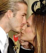 England soccer captain David Beckham kisses his wife Victoria as he holds the Officer of the Order of the British Empire medal 