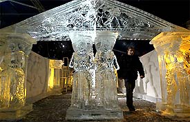 A man walks between a sculpture made out of a large chunk of ice at the Bruges Snow and Ice Sculpture Festival 2003 at Bruges
