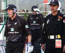 New Zealand opening batsmen Craig Cumming and Richard Jones walk past a commando of an elite police force to start the innings against Pakistan in the first one-day international on Saturday