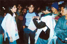 A volunteer pins an AIDS ribbon on the shirt of a youth at a roadshow
