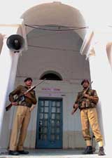Para-military troopers stand guard outside a polling booth on the eve of assembly elections in New Delhi