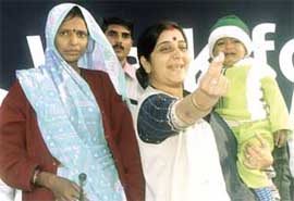 Union Minister for Health and Family Welfare Sushma Swaraj tries to pacify a wailing infant, who happens to be HIV positive. His mother, also HIV positive, looks on