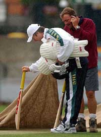 Australian captain Steve Waugh checks the pitch with a groundsman as rain falls at the Gabba in Brisbane