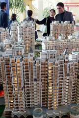 A Chinese couple looks at models of a residential property at the 14th China Shanghai Real Estate Fair 