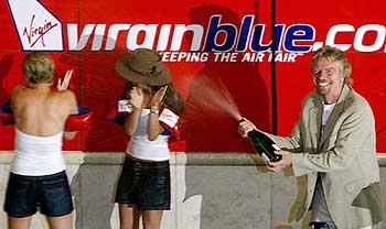 Sir Richard Branson sprays champagne over girls after his discount airline Virgin Blue was listed on the Australian Stock Exchange